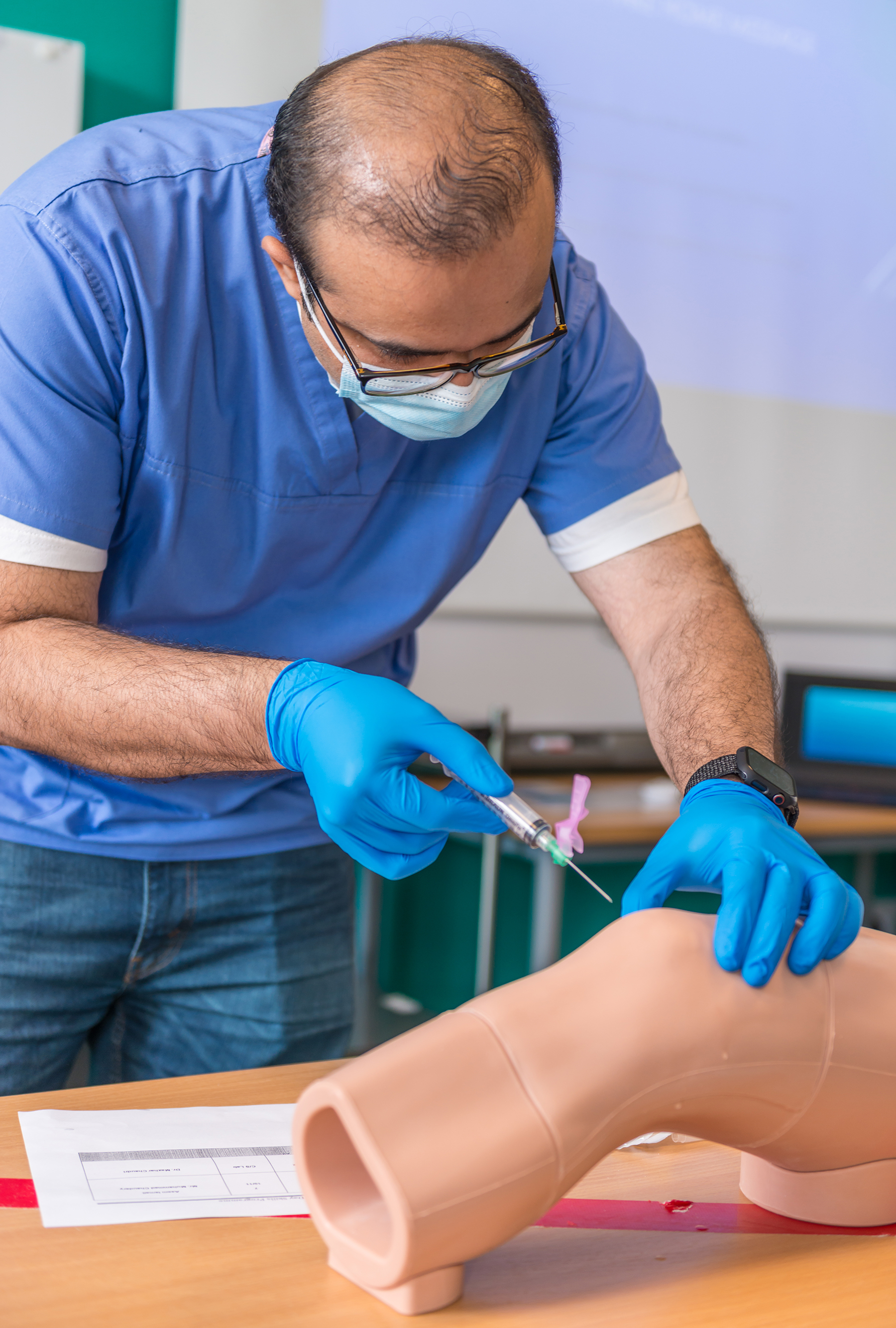 Doctor injecting a knee joint mannequin in a training workshop